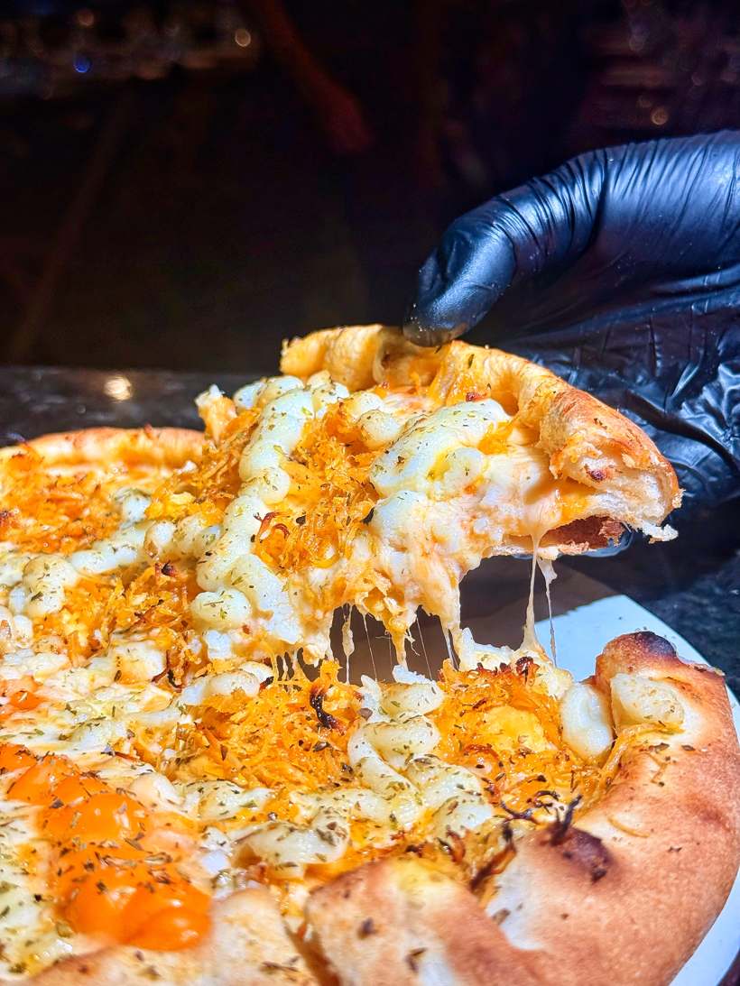 Pizza de queijos com cheddar puxando ao ser servida